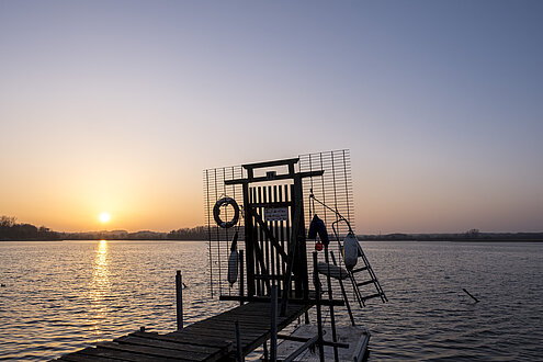 Sonnenuntergang mit lila Himmel über dem Meer. Auf dem Wasser eine Installation aus Metall.