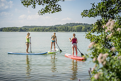 Drei Frauen auf SUPs auf einem See in der Holsteinischen Schweiz