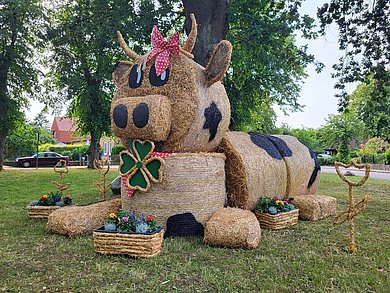 Strohfigur, auf einer Wiese, die eine Kuh darstellt