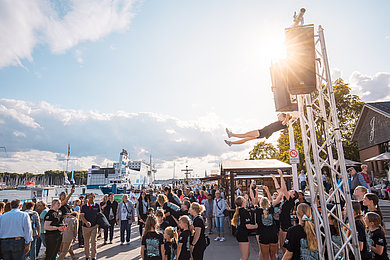 Festival travemünder Woche. Blauer Himmel, viele Menschen auf der Promenade, im Hintergrund Hafen, 
