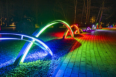 Bunte Lichter in Bögen entlang eines Weges im Kurpark Scharbeutz.
