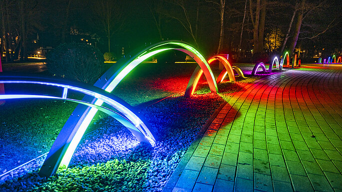 Bunte Lichter in Bögen entlang eines Weges im Kurpark Scharbeutz.