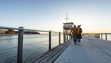 Ein Paar läuft auf der Seebrücke von Glücksburg entlang