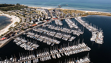 Luftbildaufnahme von der Marina Heiligenhafen. Viele weiße Boote stehen aneinandergereiht im Hafen 