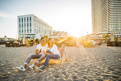 Paar trinkt Cocktails am Strand in Beachchairs