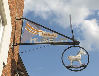 Ein Schild aus Metall, das an einer Hauswand angebracht ist, weist auf das Kindheitsmueum in Schönberg hin. 