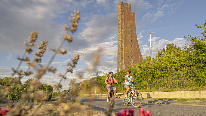 Paar macht eine Fahrradtour durch Laobe. Sie fahren am Ehrendenkmal vorbei.