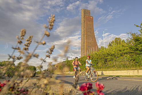 Paar macht eine Fahrradtour durch Laobe. Sie fahren am Ehrendenkmal vorbei.