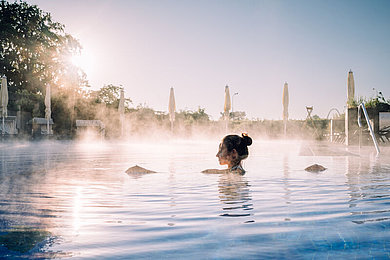 Eine Frau schwimmt im Außenbereich des Wellnessbereichs. 