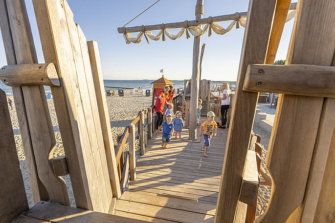 Kinder spielen auf dem Holzschiff, welches auf dem Strandspielplatz in Großenbrode steht.