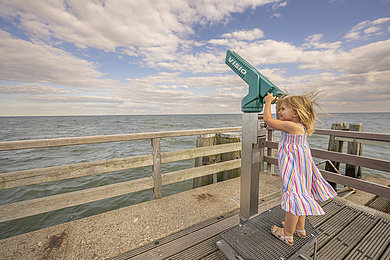 Ein kleines Kind schaut durch das Fernrohr auf der Seebrücke in Dahme.