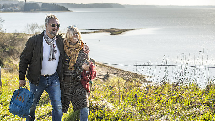Paar geht entlang der Steilküste Holnis spazieren. Recht ist die Ostsee zu sehen.