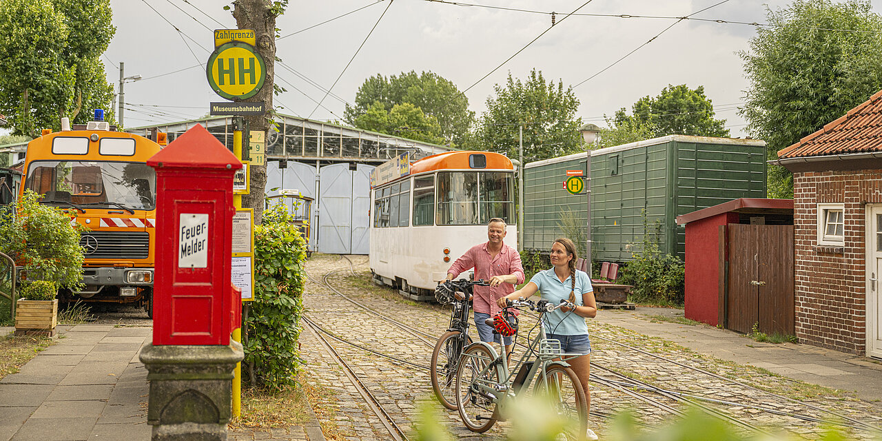 Zwei Personen die eine Radtour machen, halten bei der der Museumsbahn in Schönberg.