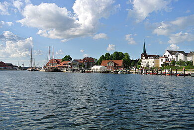Viel Wasser im Bild, im Hintergrund zeichnet sich ein Hafen ab.