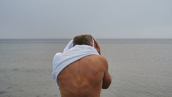 Wolfgang Kulow trocknet sich nach dem Eisbaden mit einem weißen Handtuch ab. Aber ist von hinten zu sehen.