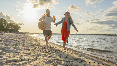 Paar geht am Strand von Heikendorf im Sonnenuntergang spazieren.