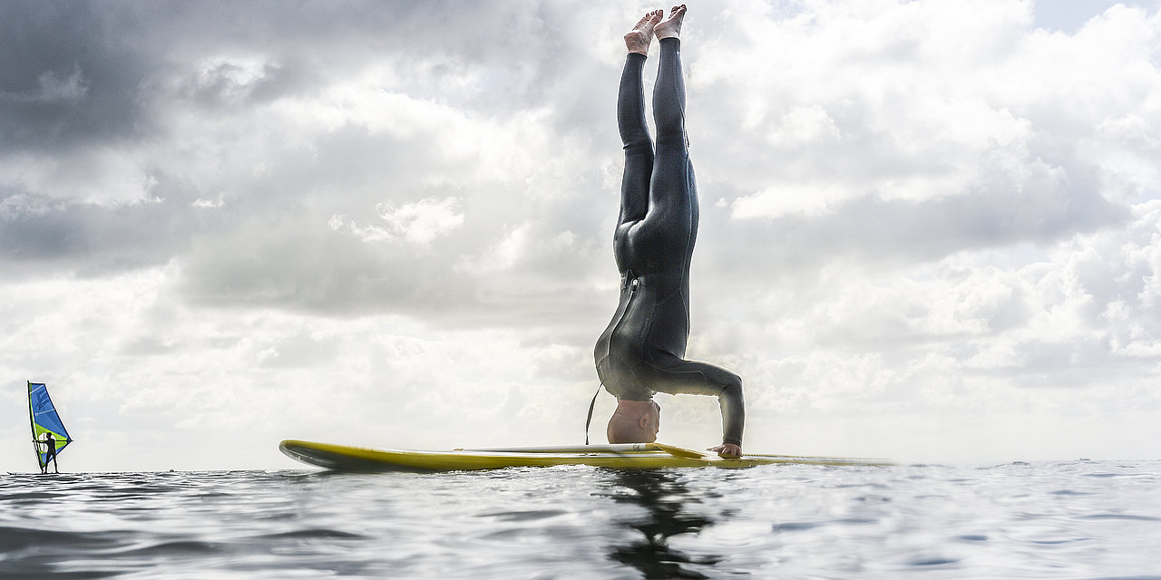 Eine Person macht einen Kopfstand auf dem SUP