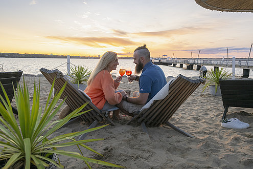 Pärchen sitzt in der Strandbar in Mönkeberg mit einem Cocktail in der Hand.