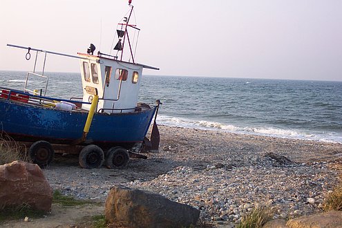 Ein Fischerboot steht am Strand.