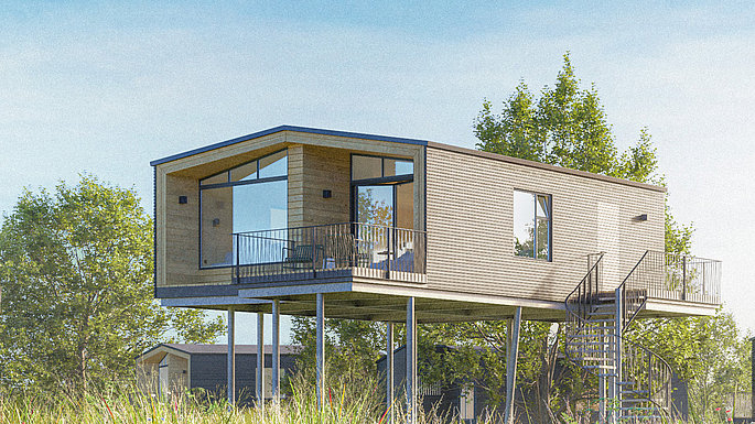 ein Haus auf Stelzen mitten auf einer grünen Wiese umgeben von Natur.