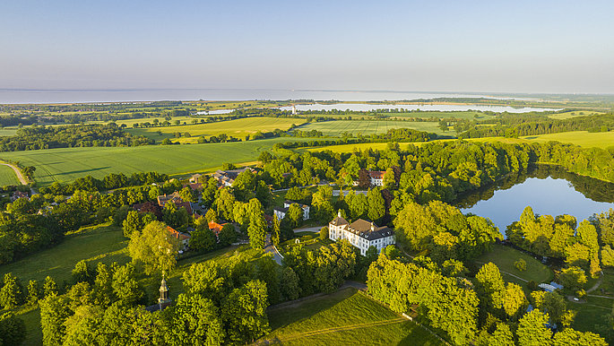 Luftbildaufnahme vom Hessenstein und Schloss Panker. Die Bäume sind grün. Es ist Sommer.