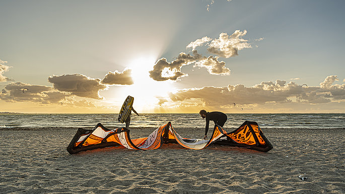 Kiter am Ostseestrand. Die Sonne geht über der Ostsee unter.