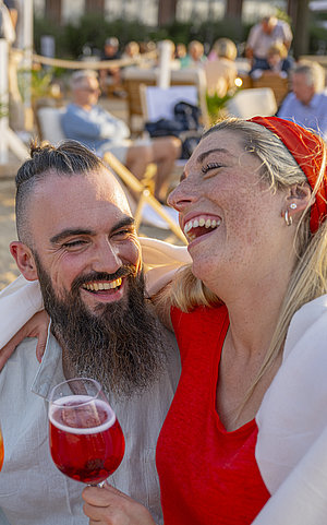 Paar am Strand mit Getränken in die Hand und am lachen
