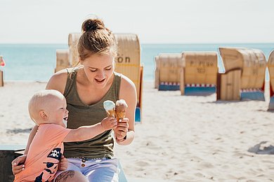 eine Mutte rmit Kind am Strand, sie essen ein Eis.