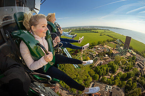 Eine Gruppe sitzt im Fahrgeschäft Highlander. Freifallturm. Sie sind gerade ganz oben.