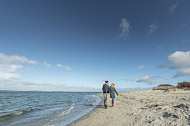 ein einsamer Strand. Zwei Menschen gehen spazieren. 