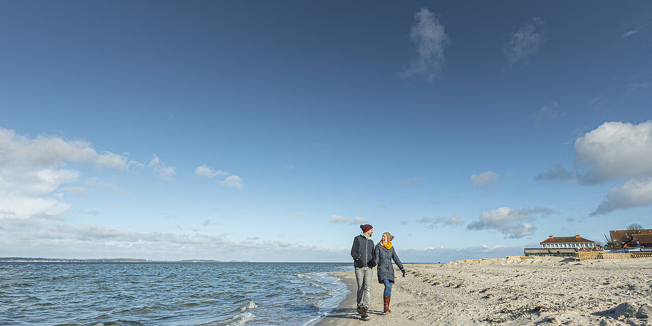 ein einsamer Strand. Zwei Menschen gehen spazieren. 