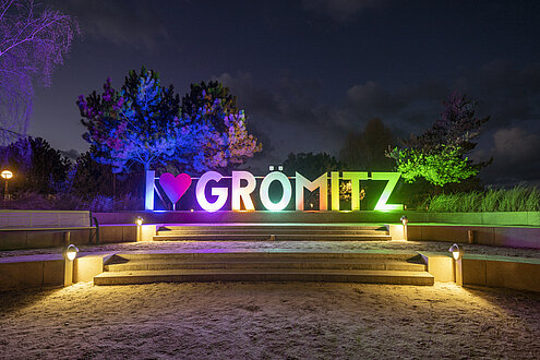 Der Schriftzug "I Symbol Herz Grömitz" am leuchtet. Jeder Buchtstabe in einer anderen Farbe.