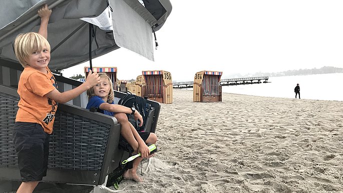 Zwei Jungs (Kinder) erkunden den Schlafstrandkorb, welcher am Strand von Eckernförde steht.