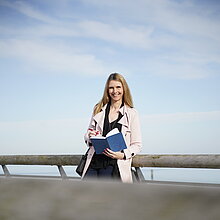 Frau auf einer Seebrücke mit Buch in der Hand
