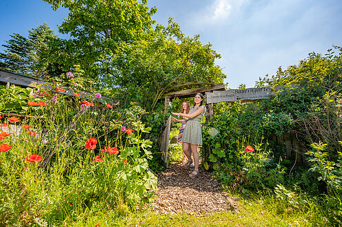 ein grüner Garten im Museumshof, Klatschmohn leuchtet links im Bild. 