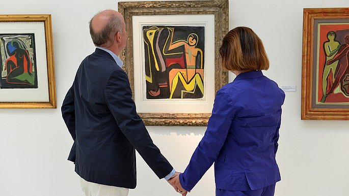 Ein Mann und eine Frau stehen Hand in Hand vor einem Bild im Museum. 