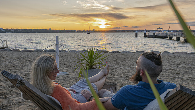 Ein paar in der Strandbar blickt dem Sonnenuntergang entgegen. 