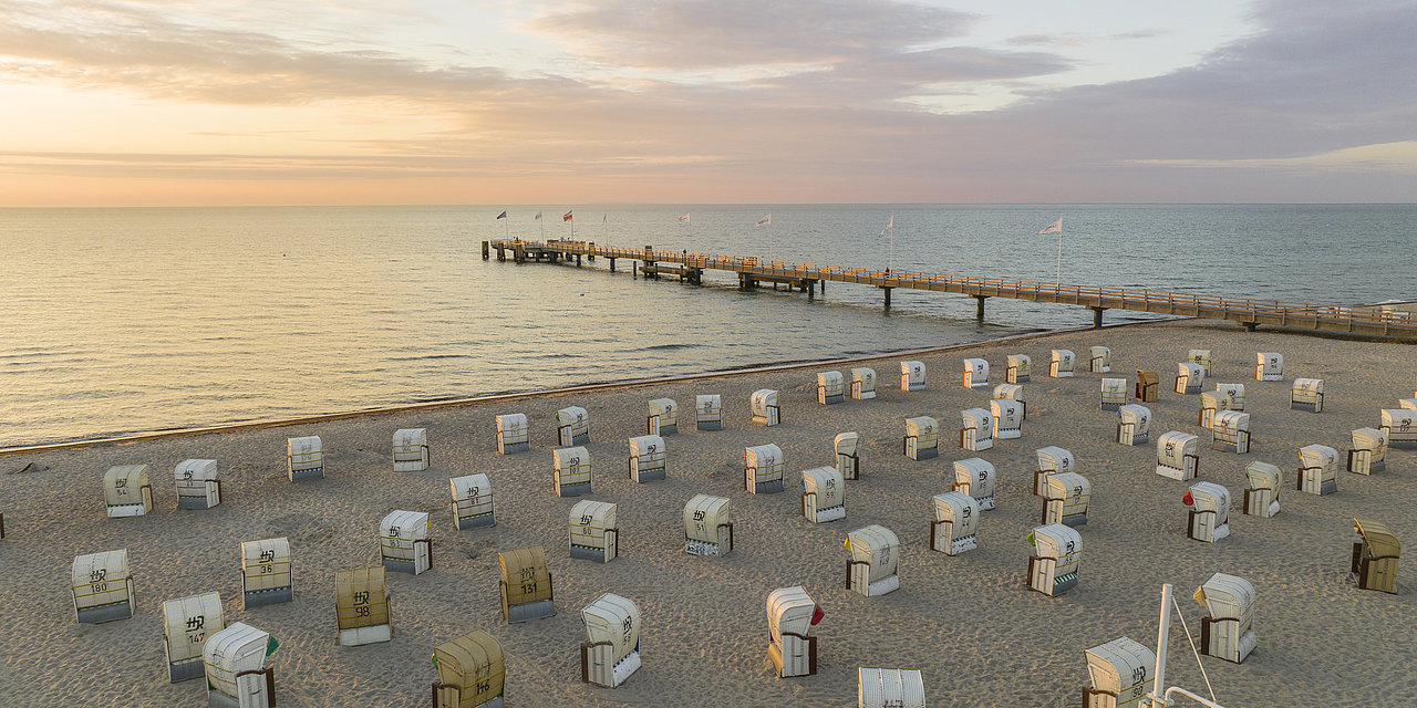 Luftbildaufnahme von dem Strand und der Seebrücke in Dahme. Auf dem Strand stehen viele Strandkörbe