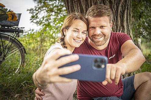 Ein Paar macht ein Selfie von sich. Neben ihnen ihre Räder. 