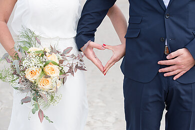 Symbolbild. Ein Hochzeitspaar formt mit den Händen ein Herz.