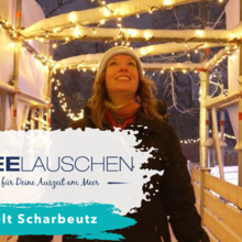 Eine Frau fährt auf der Scharbeutzer Eisbahn Schlittschuh. Es schneit, es dämmert und im Hintergrund sind die Lichterketten an.